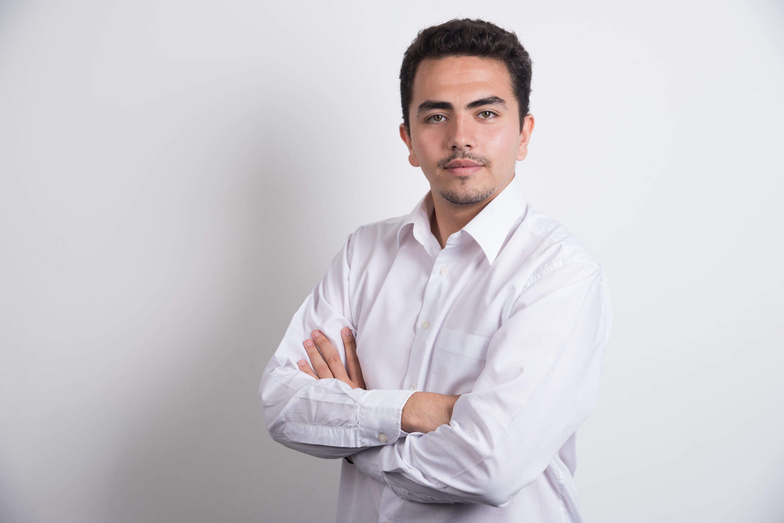 Young businessman crossing arms on white background. High quality photo